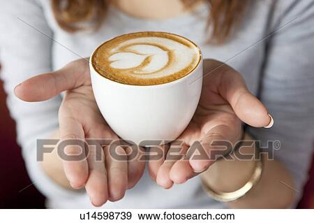Stock Photo - Coffee, Young woman holding a cup of cappuccino with pattern. Fotosearch