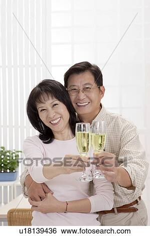 Couple, Couple bonding together and holding glasses of drink with smile View Large Photo Image Stock Photograph - Couple, Couple bonding together and holding glasses of drink with smile. Fotosearch