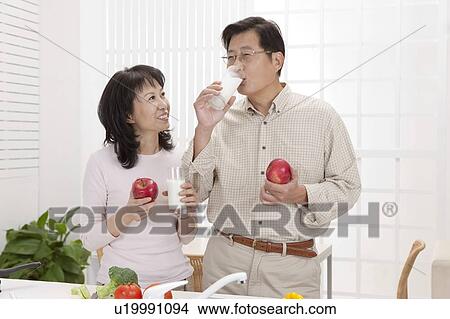 Picture - Couple, Couple holding apple and glass of drink together. Fotosearch