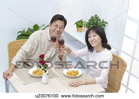 Stock Image - Couple, Couple holding glass of wine and looking up with smile. Fotosearch