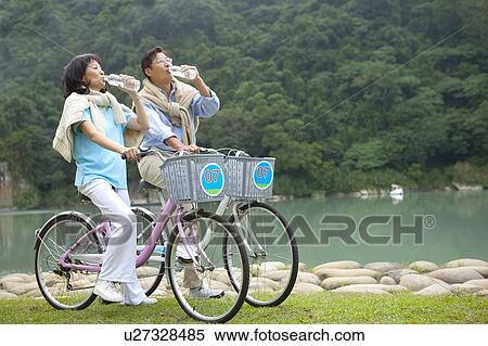 Stock Photography - Couple, Couple riding on bikes and drinking water together. Fotosearch
