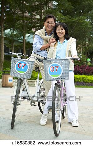 Couple, Couple riding on bikes, holding hands and smiling View Large Photo Image Stock Image - Couple, Couple riding on bikes, holding hands and smiling. Fotosearch