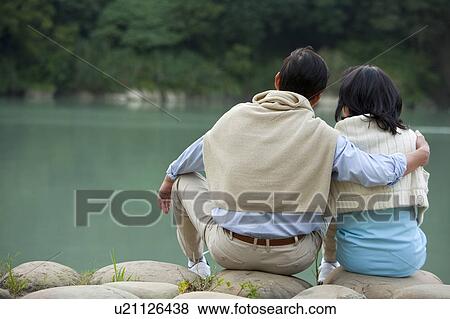Couple, Couple sitting near the lake with arm around View Large Photo Image Stock Photo - Couple, Couple sitting near the lake with arm around. Fotosearch