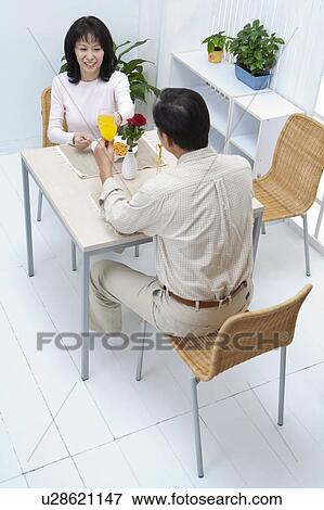 Stock Photo - Couple, Couple sitting near the table and toasting with smile. Fotosearch