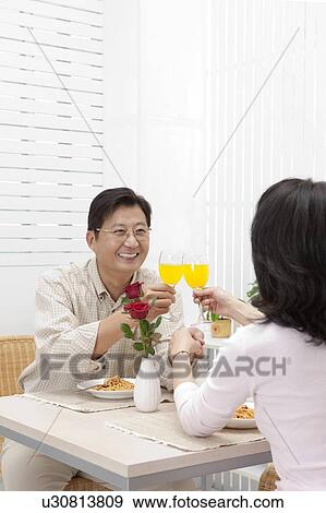 Stock Photo - Couple, Couple sitting near the table and toasting with smile. Fotosearch