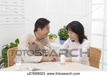Stock Image - Couple, Couple sitting on the table and holding hands with smile. Fotosearch