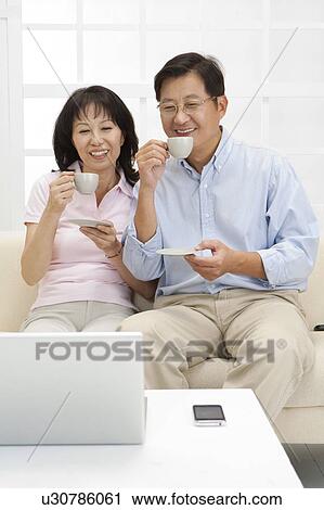 Stock Image - Couple, Couple sitting together and drinking cup of tea. Fotosearch