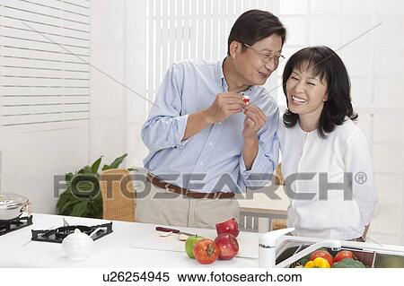 Stock Photography - Couple, Couple standing in kitchen and smiling happily. Fotosearch