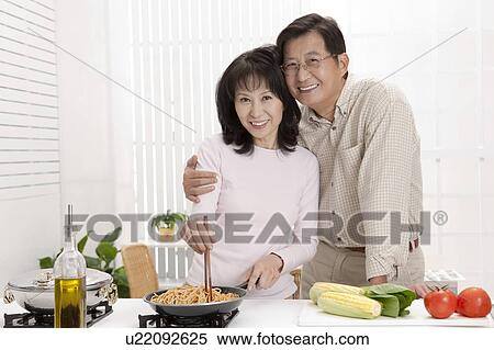 Couple, Couple standing together and cooking food in the kitchen View Large Photo Image Stock Photography - Couple, Couple standing together and cooking food in the kitchen. Fotosearch