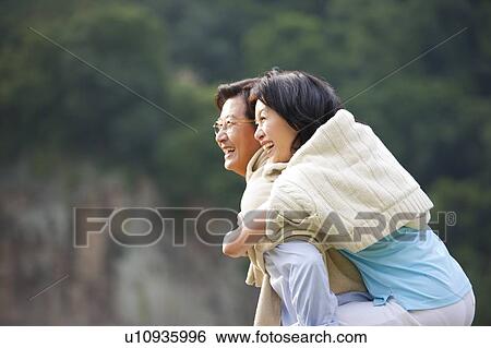 Couple, Wife is on husband's back and smiling happily View Large Photo Image Stock Photograph - Couple, Wife is on husband's back and smiling happily. Fotosearch