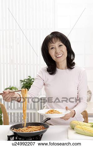 Stock Photo - Couple, Woman holding a plate of noodles with smile. Fotosearch