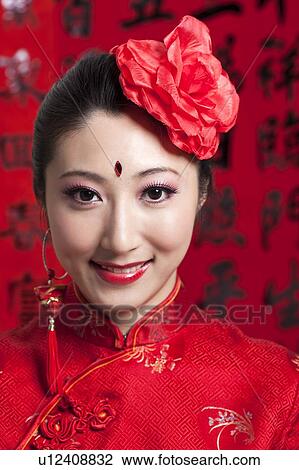 Stock Image - New Year, Close-up of young woman wearing Chinese traditional clothing and a red flower with smile,. Fotosearch