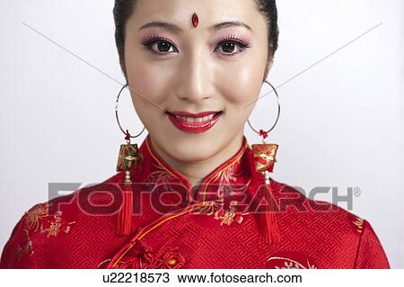 Stock Image - New Year, Close-up of young woman wearing Chinese traditional clothing and smiling at the camera. Fotosearch
