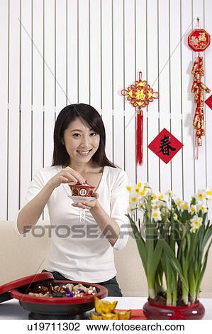 Stock Image - New Year, Young woman holding a cup of tea and smiling at the camera,. Fotosearch