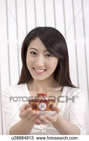 Stock Image - New Year, Young woman holding a cup of tea and smiling at the camera. Fotosearch