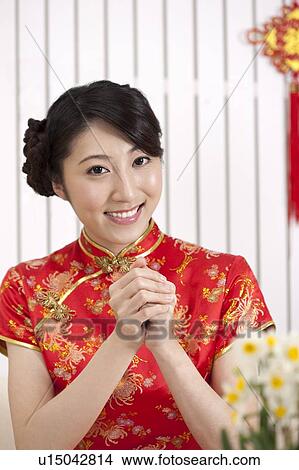 Picture - New Year, Young woman wearing Chinese traditional clothing and greeting with smile. Fotosearch