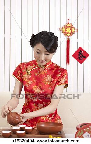 Picture - New Year, Young woman wearing Chinese traditional clothing and making tea ceremony with smile. Fotosearch