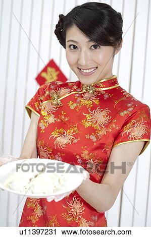 New Year, Young woman wearing Chinese traditional clothing and holding a plate of dumplings with smile View Large Photo Image Stock Image - New Year, Young woman wearing Chinese traditional clothing and holding a plate of dumplings with smile. Fotosearch