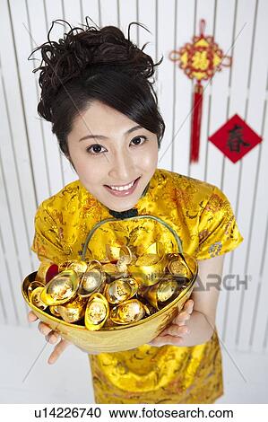 New Year, Young woman wearing Chinese traditional clothing and holding a basket of gold ingots with smile View Large Photo Image Stock Image - New Year, Young woman wearing Chinese traditional clothing and holding a basket of gold ingots with smile. Fotosearch