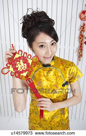 New Year, Young woman wearing Chinese traditional clothing and holding a decoration View Large Photo Image Stock Image - New Year, Young woman wearing Chinese traditional clothing and holding a decoration. Fotosearch