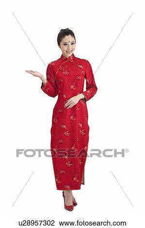 Stock Image - New Year, Young woman wearing Chinese traditional clothing and reaching out one hand with smile. Fotosearch