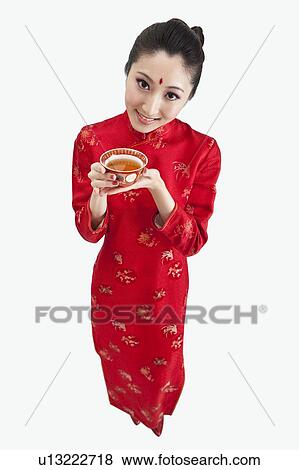 Stock Photo - New Year, Young woman wearing Chinese traditional clothing and holding a cup of tea with smile. Fotosearch