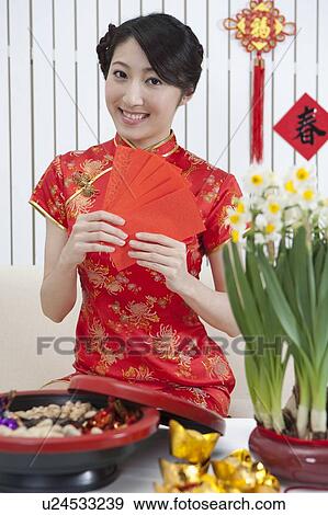 Stock Photo - New Year, Young woman wearing Chinese traditional clothing and holding red envelopes with smile. Fotosearch