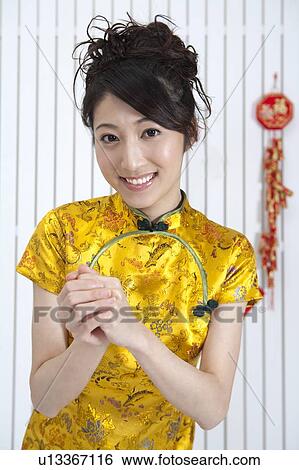 Stock Photograph - New Year, Young woman wearing Chinese traditional clothing and greeting with smile. Fotosearch