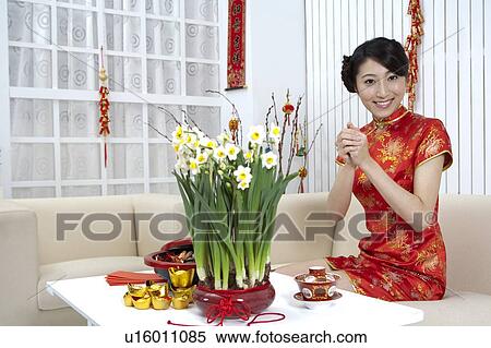 Stock Photography - New Year, Young woman wearing Chinese traditional clothing and greeting with smile. Fotosearch