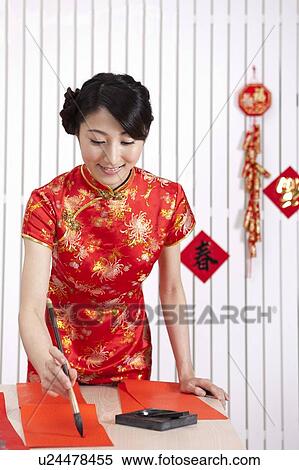 New Year, Young woman wearing Chinese traditional clothing and writing with ink brush with smile View Large Photo Image Stock Photography - New Year, Young woman wearing Chinese traditional clothing and writing with ink brush with smile. Fotosearch