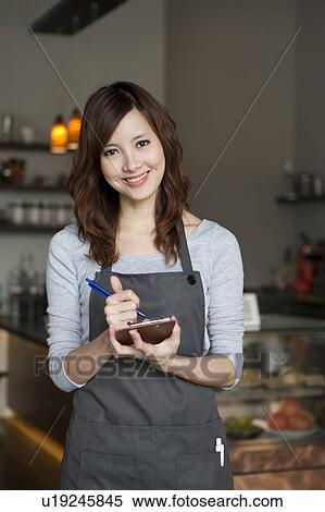 Waiter, Waitress, Young waitress writing on a notebook and looking at the camera with smile View Large Photo Image Stock Photography - Waiter, Waitress, Young waitress writing on a notebook and looking at the camera with smile. Fotosearch