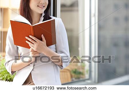 Woman holding a book and looking away with smile View Large Photo Image Stock Image - Woman holding a book and looking away with smile. Fotosearch