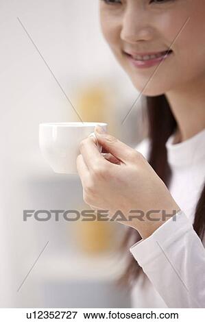 Stock Photo - Woman holding a cup and smiling. Fotosearch