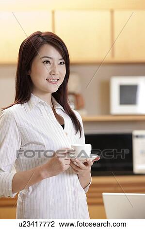 Woman holding a cup of coffee and looking away with smile View Large Photo Image Stock Image - Woman holding a cup of coffee and looking away with smile. Fotosearch