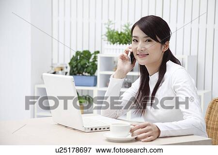 Woman holding a cup, using laptop and looking at the camera with smile View Large Photo Image Stock Photo - Woman holding a cup, using laptop and looking at the camera with smile. Fotosearch