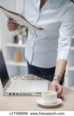 Woman holding a newspaper and a cup of coffee View Large Photo Image Stock Photography - Woman holding a newspaper and a cup of coffee. Fotosearch