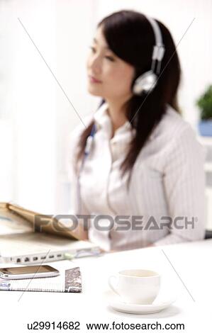 Stock Image - Woman holding a notebook and listening music. Fotosearch