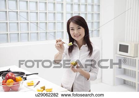 Woman holding a spoon of fruit and looking at the camera with smile View Large Photo Image Stock Image - Woman holding a spoon of fruit and looking at the camera with smile. Fotosearch