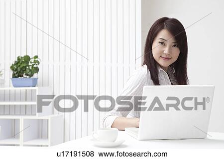 Woman using laptop and smiling at the camera View Large Photo Image Stock Photo - Woman using laptop and smiling at the camera. Fotosearch