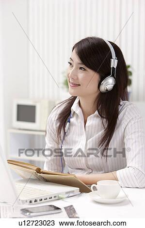 Stock Image - Woman wearing headphone and looking away with smile. Fotosearch