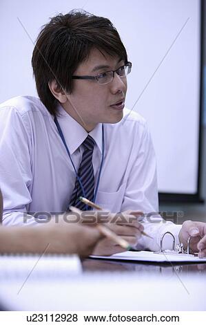 Stock Photo - Young man holding pencil and looking away. Fotosearch
