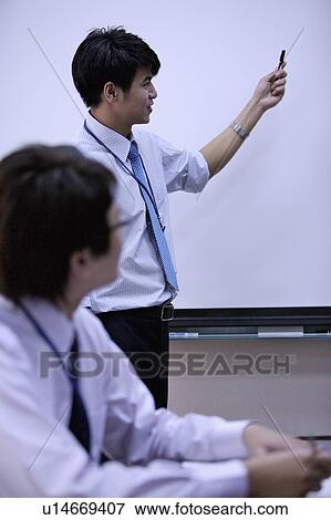 Stock Photo - Young man standing and pointing away. Fotosearch