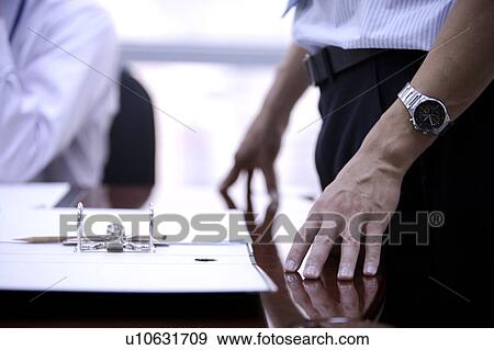 Young man standing and wearing a wristwatch View Large Photo Image Stock Photo - Young man standing and wearing a wristwatch. Fotosearch