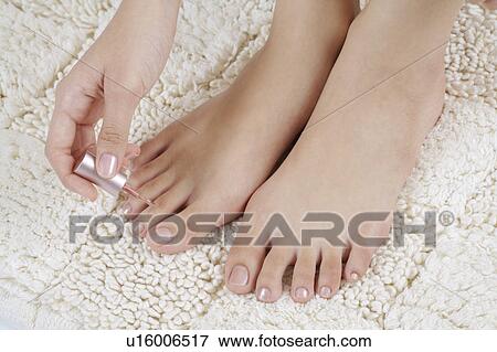 Stock Photo - Young woman applying nail polish on toenail. Fotosearch