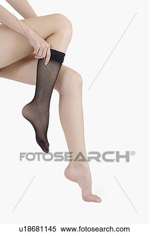 Stock Photography - Young woman getting dressed on one leg with stocking. Fotosearch