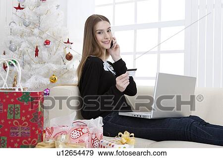 Young woman holding mobile phone and using laptop with smile View Large Photo Image Stock Photo - Young woman holding mobile phone and using laptop with smile. Fotosearch