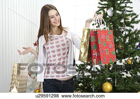 Young woman holding shopping bags and smiling happily View Large Photo Image Stock Photo - Young woman holding shopping bags and smiling happily. Fotosearch