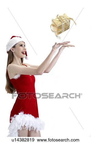 Young woman in Christmas clothing laughing with gift in mid-air View Large Photo Image Stock Photo - Young woman in Christmas clothing laughing with gift in mid-air. Fotosearch