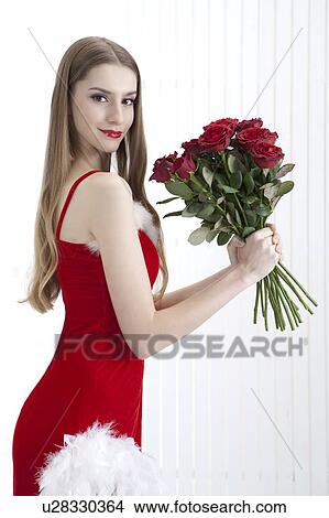 Picture - Young woman in red dress and holding red roses with smile. Fotosearch