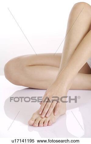 Stock Photography - Young woman sitting on floor and massaging foot. Fotosearch